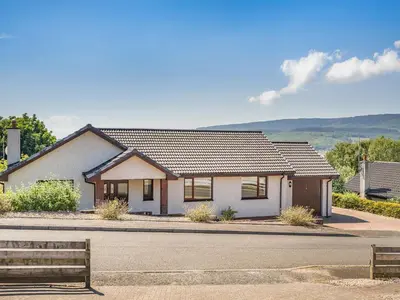 a white house with a bench in front of it at Kilbride in Lamlash