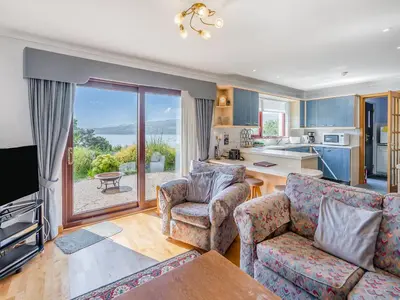a living room with a couch and chairs and a kitchen at Kilbride in Lamlash