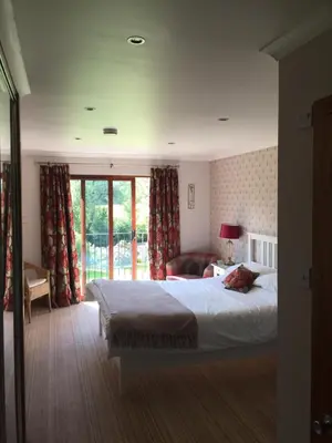 a bedroom with a bed and a chair and windows at Riverside House in Callander