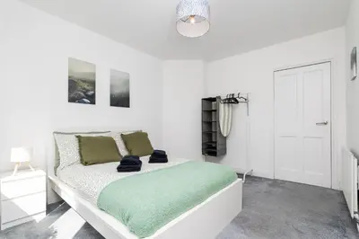 a white bedroom with a bed with a green blanket at 3Bedroom Apartment-Free Parking in Falkirk