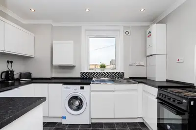 a white kitchen with a washer and dryer at 3Bedroom Apartment-Free Parking in Falkirk
