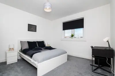 a bedroom with a bed and a desk and a window at 3Bedroom Apartment-Free Parking in Falkirk