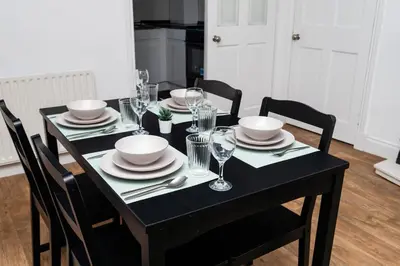 a black dining room table with plates and glasses at 3Bedroom Apartment-Free Parking in Falkirk