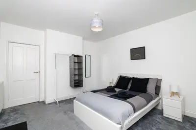 a white bedroom with a bed and a white door at 3Bedroom Apartment-Free Parking in Falkirk