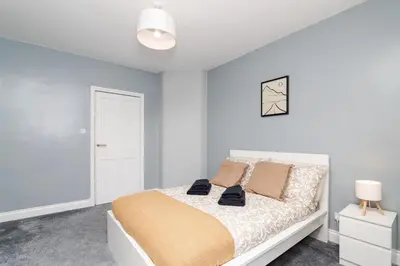 a white bedroom with a bed with blue walls at 3Bedroom Apartment-Free Parking in Falkirk