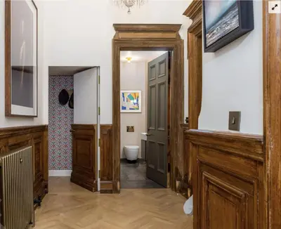 a hallway with a bathroom with a toilet and a door at Luxury Wood panelled West End GF Flat in Edinburgh