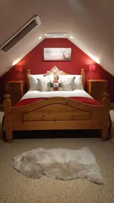a bedroom with a wooden bed with a red wall at A Cozy Bothy Retreat with Hot Tub in Keilour