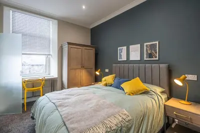 a bedroom with a bed with blue walls and yellow pillows at 3BR Gem West End Walk to Glasgow Uni Parking in Glasgow