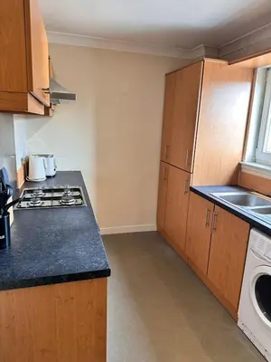 a kitchen with wooden cabinets and a stove top oven at 2BR Flat Free Parking Near Hampden and O2 Academy in Glasgow