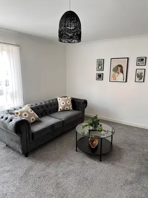 a living room with a black couch and a table at 2BR Flat Free Parking Near Hampden and O2 Academy in Glasgow
