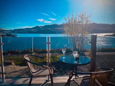 a table and chairs on a deck with a view of the water at Luxury Pod and Sauna with Fantastic Sea Views in Oban