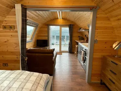 a bedroom in a log cabin with a bed and a kitchen at Luxury Pod and Sauna with Fantastic Sea Views in Oban