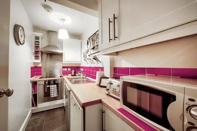 a kitchen with pink and white cabinets and counters at Grindlay St - Fantastic 2BR in Theatre District in Edinburgh