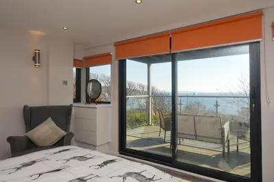 a bedroom with a bed and a large glass window at Cliff Top - Bubbling Springs in Wemyss Bay