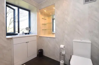a bathroom with a toilet and a sink and a window at Cliff Top - Bubbling Springs in Wemyss Bay