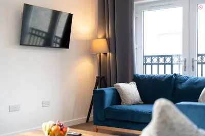 a living room with a blue couch and a window at Glenfiddich Apartment in Oban