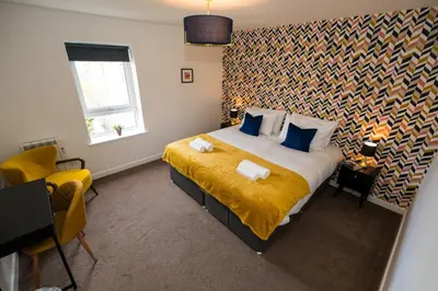 a bedroom with a large bed with a yellow blanket at Glenfiddich Apartment in Oban
