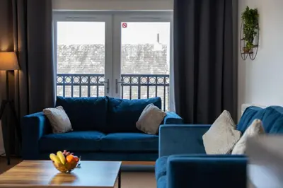 a living room with a blue couch and a table at Glenfiddich Apartment in Oban