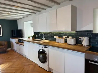 a kitchen with white cabinets and a washing machine at Eldon Cottage in Isle of Arran
