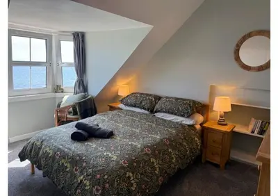a bedroom with a large bed and a window at Eldon Cottage in Isle of Arran