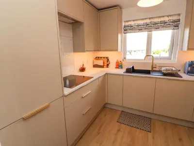 a kitchen with white cabinets and a sink and a window at The Paddock in Kirkcowan