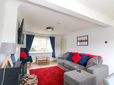 a living room with a couch and a red rug at 3 Whin Bank in Oban