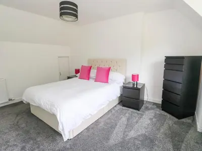 a bedroom with a large white bed with pink pillows at 3 Whin Bank in Oban