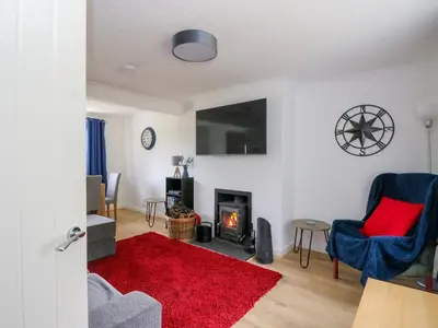 a living room with a fireplace and a red rug at 3 Whin Bank in Oban