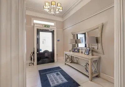 a hallway with a desk and a door with a mirror at Cairn BNB Introduces Blythswood Apartments - Experience exceptional luxury living in Glasgow's most desirable location in Glasgow