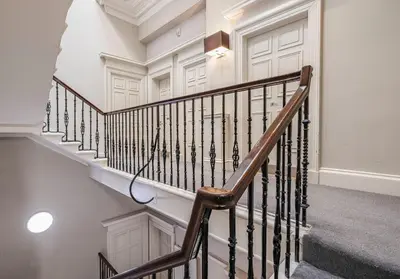 a staircase in a home with white walls and wooden railings at Cairn BNB Introduces Blythswood Apartments - Experience exceptional luxury living in Glasgow's most desirable location in Glasgow