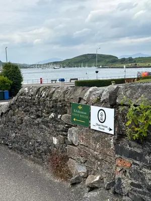 a sign on a stone wall next to a body of water at Oban House House in Oban