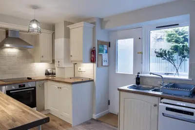 a kitchen with white cabinets and a sink and a window at Cottage in Crieff in Crieff