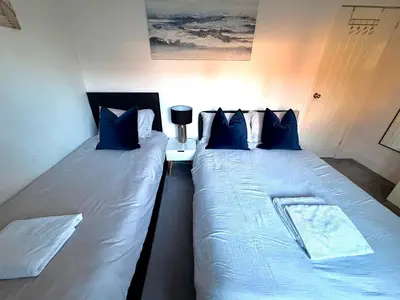 a bedroom with two beds with blue pillows at South Gyle House - SuperFast WiFi and Free Parking - 7 minutes from Edinburgh Airport in Edinburgh