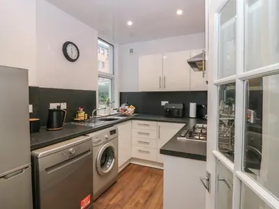 a kitchen with white cabinets and a washer and dryer at 60E Wellgate in Lanark