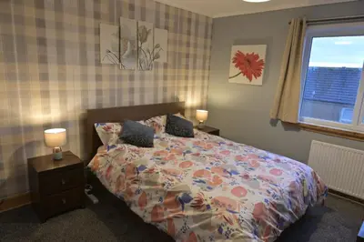 a bedroom with a bed and two lamps and a window at Stylish Coastal Retreat in Saltcoats in Stevenston
