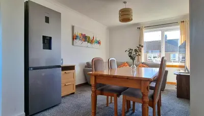 a kitchen with a wooden table and a refrigerator at Stylish Coastal Retreat in Saltcoats in Stevenston