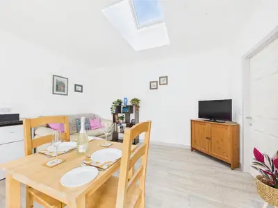 a dining room with a wooden table and a tv at Bathach Beag in Oban