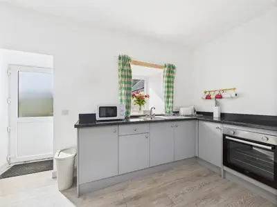 a kitchen with white cabinets and a sink and a mirror at Bathach Beag in Oban