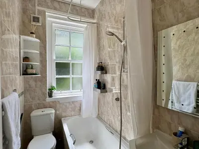 a bathroom with a tub and a toilet and a shower at Stylish 2BR Grassmarket Flat with Castle Views & PS5 in Edinburgh