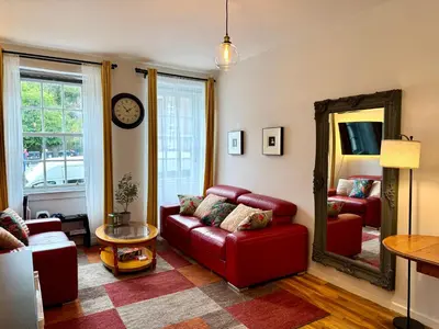 a living room with a red couch and a mirror at Stylish 2BR Grassmarket Flat with Castle Views & PS5 in Edinburgh