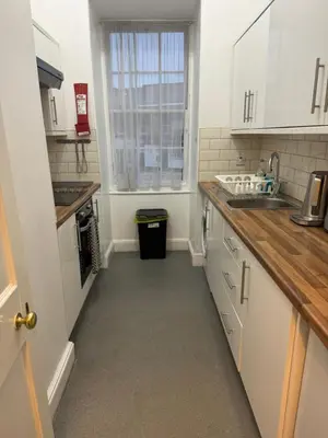 a kitchen with white cabinets and a sink and a window at 52, Charlotte Street Apartments in Glasgow