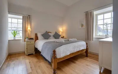 a bedroom with a large bed with two windows at Penninghame Estate - Wallace Apartment in Challoch