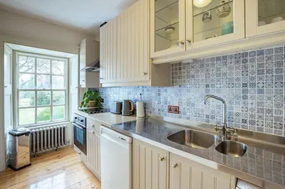 a kitchen with white cabinets and a sink at Penninghame Estate - Stewart Apartment in Challoch