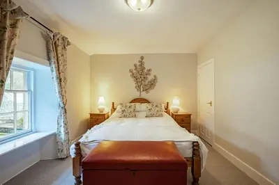 a bedroom with a bed and a window at Penninghame Estate- Gardeners Cottage in Challoch