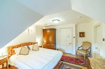 a bedroom with a large white bed and a chair at Penninghame Estate - Tower Apartment in Challoch