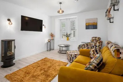 a living room with yellow furniture and a flat screen tv at Stunning 2BR Apt - Central High Street Location in Oban