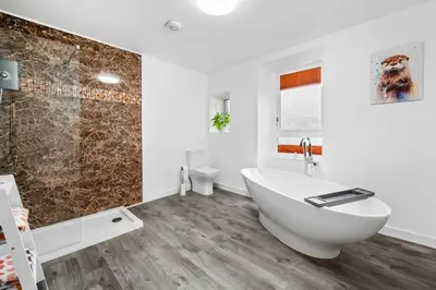 a white bathroom with a tub and a shower at Stunning 2BR Apt - Central High Street Location in Oban