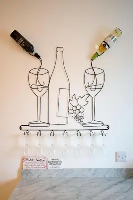 three wine glasses and wine bottles on a shelf at Stunning 2BR Apt - Central High Street Location in Oban