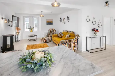a living room with a table and a yellow couch at Stunning 2BR Apt - Central High Street Location in Oban