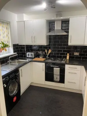 a kitchen with white cabinets and a washer at Millview house in Airdrie